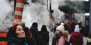 Menschen stehen auf der Straße in Rauchschwaden und gucken sich unzufrieden um