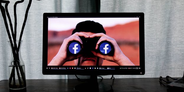 Ein Mann ist auf einem Bildschirm zu sehen, er hält sich ein Fernglas vor die Augen, in dessen Linsen das Facebook-Logo prangt