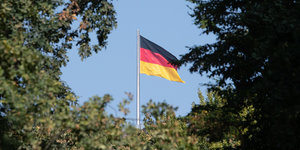 Eine Deutschlandfahne hinter Bäumen