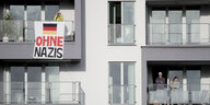 An einer grauen Hausfassade hängt ein Schild auf dem Ohne Nazis steht