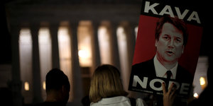 Vor dem Obersten Gericht in Washington hält eine Frau ein Plakat mit dem Gesicht von Brett Kavanaugh und der Aufschrift "Kava Nope"