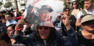 Eine Frau hält ein Plakat mit einem Foto von Alberto Fujimori, daneben sammeln sich weitere Personen