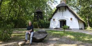 Ein Mensch sitzt vor der Schilfdachkirche