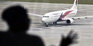 In Kuala Lumpur sieht man den Schatten eines Menschen vor einem Flugzeug auf dem Rollfeld