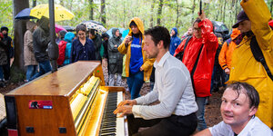 Im Hambacher Forst demonstrieren Menschen gegen die Rodung des Waldes. Ein Mann spielt Klavier