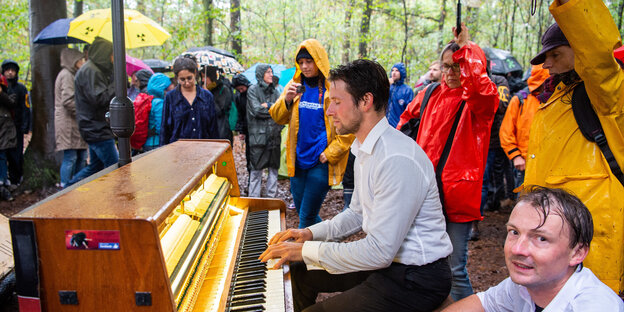 Im Hambacher Forst demonstrieren Menschen gegen die Rodung des Waldes. Ein Mann spielt Klavier