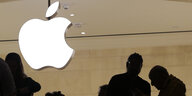 Ein Apple-Logo hängt über den Silhouetten mehrerer Menschen