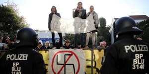 Drei junge Menschen mit einem Plakat gegen Nazis
