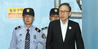 Ein Mann im Anzug wird von zwei Polizisten geführt. Es ist Lee Myung-bak