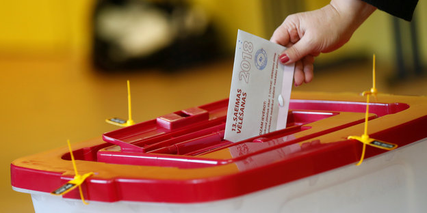 In Lettland wirft eine Person einen Stimmzettel in eine Wahlurne