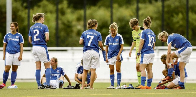 Fußballerinnen von Holstein Kiel stehen auf einem Fußballplatz.