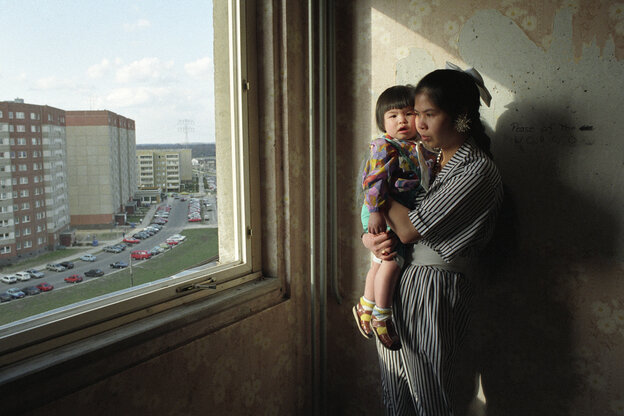 Eine Frau mit Kind steht an einem Fenster