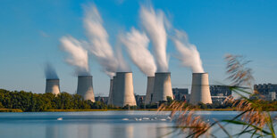 Hinter einem Karpfenteich steigt Wasserdampf aus den Kühltürmen des Braunkohlekraftwerkes Jänschwalde der Lausitz Energie Bergbau AG