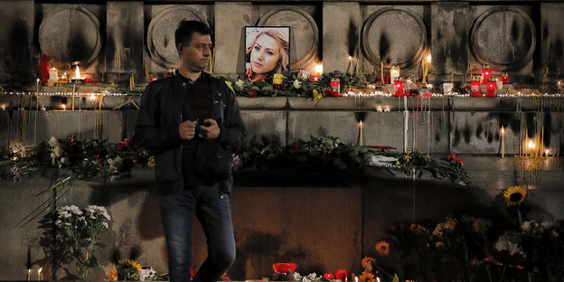 Ein Mann steht vor einem Foto der ermoderteten Journalistin Viktoria Marinova
