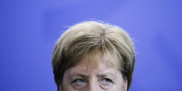 Das Gesicht von Angela Merkel von der Nase hin nach oben vor einer violetten Wand