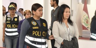 Eine Polizistin führt Keiko Fujimori vor sich her