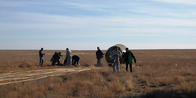 Rettungsmannschaften stehen neben der notgelandeten russischen Sojus-Kapsel in der Steppe von Kasachstan