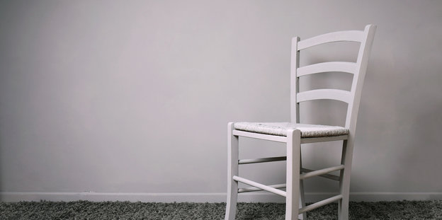 Ein weißer Stuhl steht in einem ansonsten leeren Zimmer