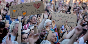 Menschen halten auf der unteilbar-Demo Schilder hoch, auf einem steht: Hass ist krass, Liebe ist krasser