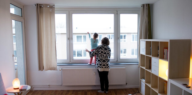 Eine Frau und ein kleines Mädchen blicken aus einem Fenster.