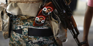 Zwei Sticker mit Assads Gesicht sind auf eine AK-47 geklebt
