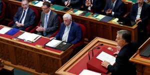 Männliche Politiker sitzen in Ungarns Parlament und hören Ministerpräsident Viktor Orban zu