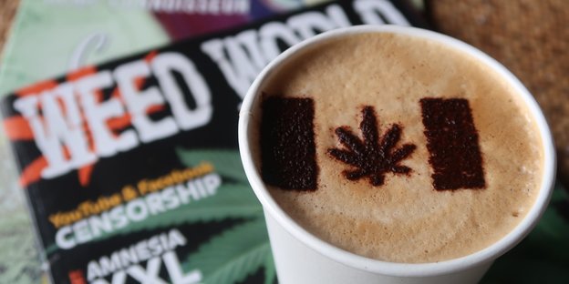 Kaffeebecher mit Hanfblatt-Deko neben Zeitschrift "Weed World"