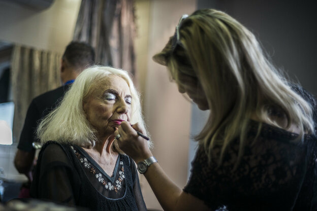 Eine ältere Frau wird von einer Maskenbildnerin geschminkt