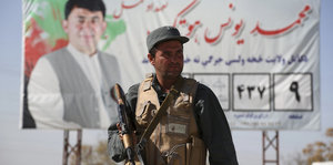 Vor einem Checkpoint in Kabul steht ein bewaffneter Polizist