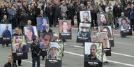 Menschen auf einer Demonstration in Chemnitz tragen große Fotografien von ermorderten Personen