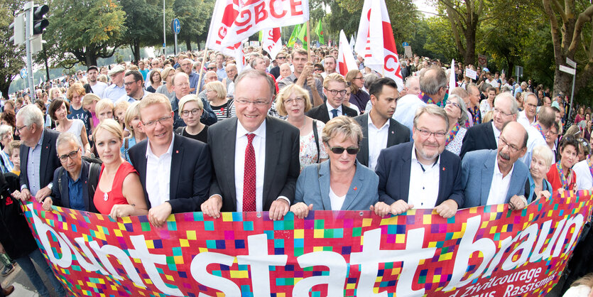 Viele Menschen tragen ein breites Banner auf einer Demo vor sich her