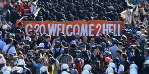 Eine Menschenmenge trägt ein Banner mit der Aufschrift "G20 Welcome to Hell"