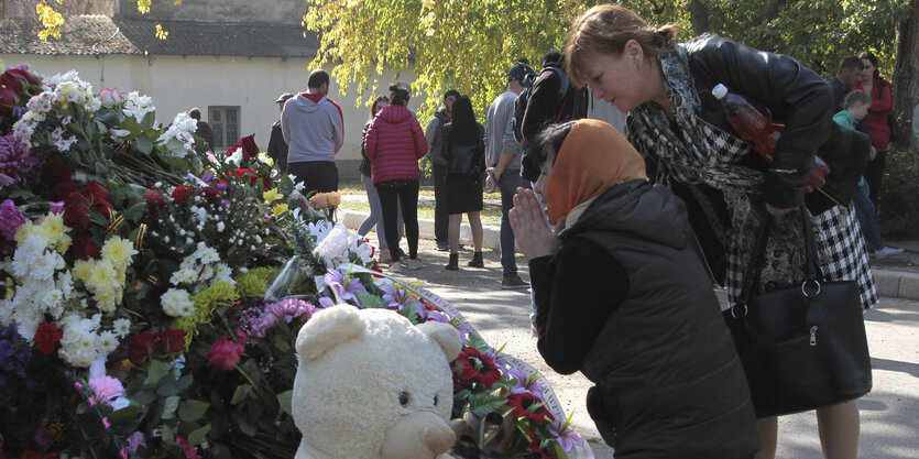 Trauernde vor Blumen