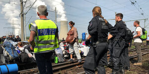 Aktivisten des Anti-Braunkohle-Bündnisses "Ende Gelände" blockieren Schienen, im Hintergrund ist ein Kraftwerk, im Vordergrund steht Polizei