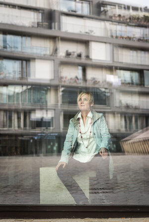 Eine Frau sitzt hinter einer Glasscheibe, es ist die Architektin Benita Braun-Feldweg Eine Frau sitzt hinter einer Glasscheibe, es ist die Architektin Benita Braun-Feldweg