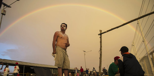 Ein Migrant aus Honduras trägt Sonnenschutz auf seinem Gesicht und steht auf Brücke