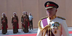 ein Mann in Prunkuniform, im Hintergrund Soldaten