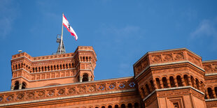 Das Bild zeigt einen Turm des Berliner Rathauses, auf dem die Flagge des Landes Berlin weht.