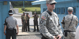 Soldaten in verschiedenen Uniformen stehen auf einer Straße herum