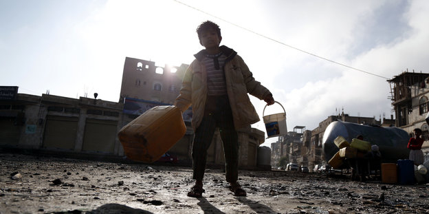 Ein Junge im Jemen mit zwei großen Kanistern