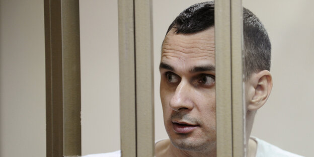 Oleg Senzow schaut durch Gitterstäbe in einem Gerichtssaal