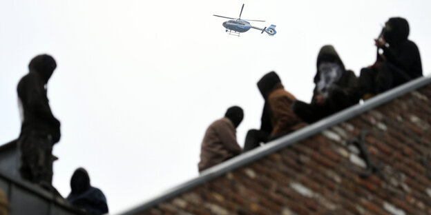 Braunkohlegegner auf einem Dach, darüber ein Hubschrauber