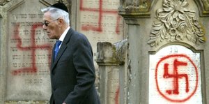 Ein Mann mit Kipa begutachtet den mit Hakenkreuzen geschändeten Friedhof in Colmar