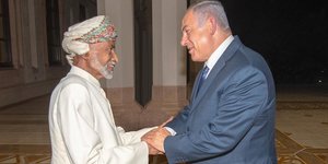 Der omanische Sultan Qaboos und der israelische Ministerpräsident Netanjahu stehen sich gegenüber und schütteln Hände