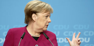 Merkel guckt zur Seite und gestikuliert mit der linken Hand