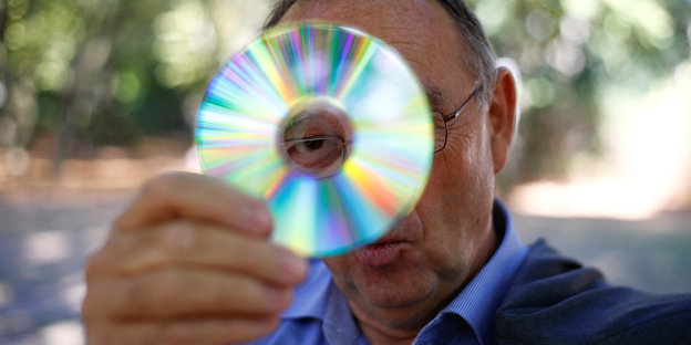Norbert Walter-Borjans hält sich eine CD vors Gesicht