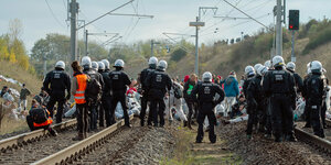 Aktivisten und Polizisten stehen auf einem Gleis