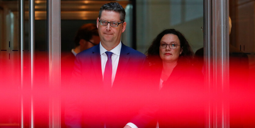 Andrea Nahles und Thorsten Schäfer-Gümbel verlassen ein Gebäude, ein roter Lichtreflex zieht sich als Streifen quer durchs Bild