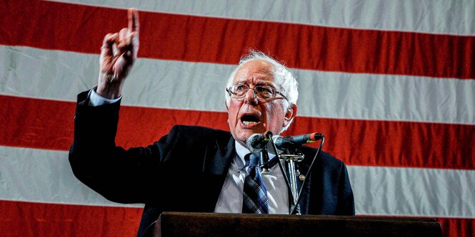 Bernie Sanders steht vor der US-Flagge an einem Pult und redet