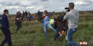 Eine Frau mit Kamera stellt flüchtenden Kindern ein Bein